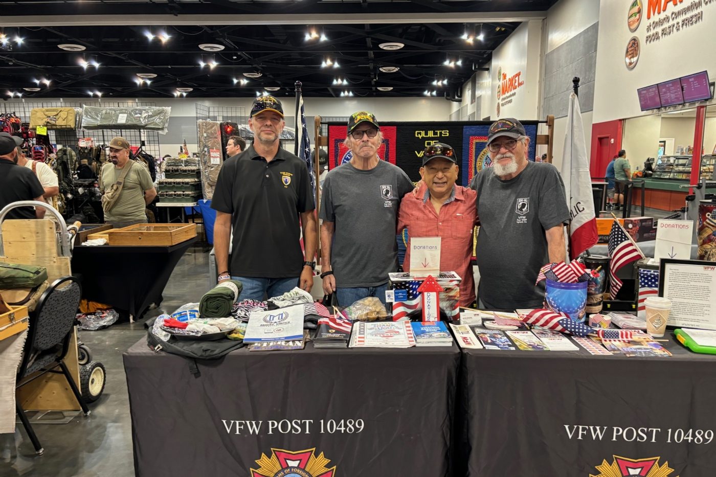 Four VFW Post 10489 members standing behind an information table marked VFW Post 10489
